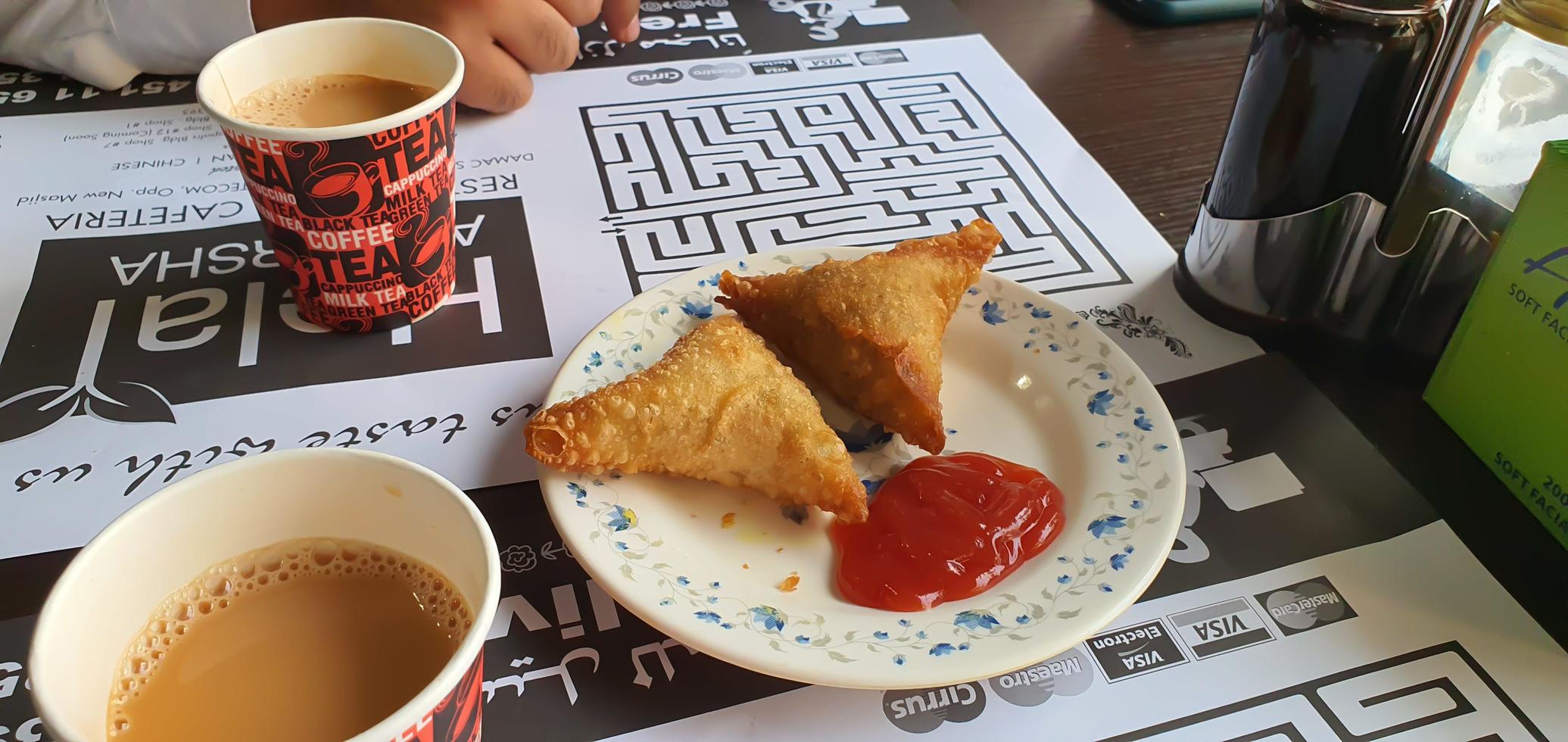 Samosa - is a crispy and spicy Indian triangle shape snack which has crisp outer layer of maida filling of mashed potato, peas and spices with tea photo