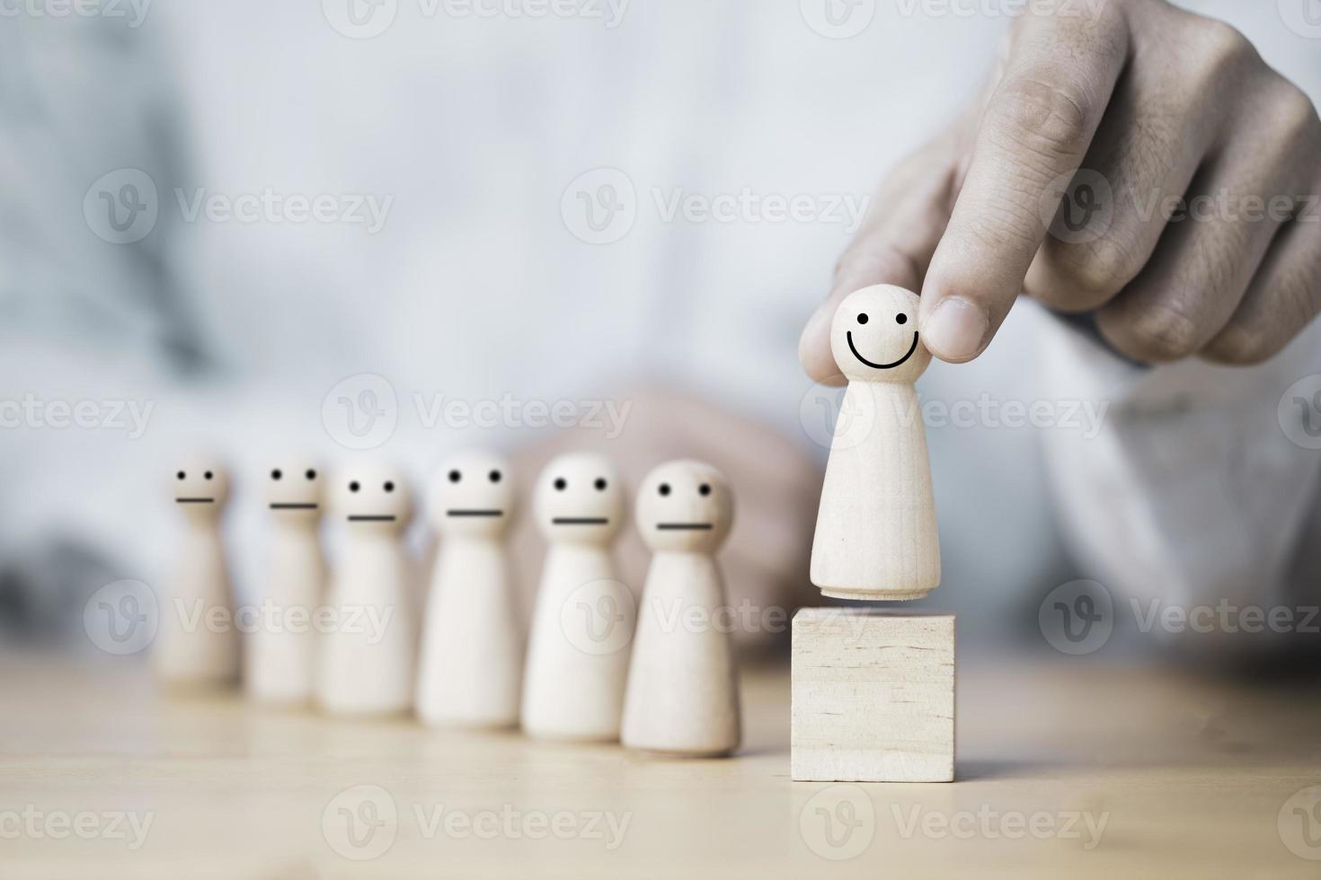 Hand holding smiley wooden model figure on wooden cube block , promotion to leadership and management growth concept. photo