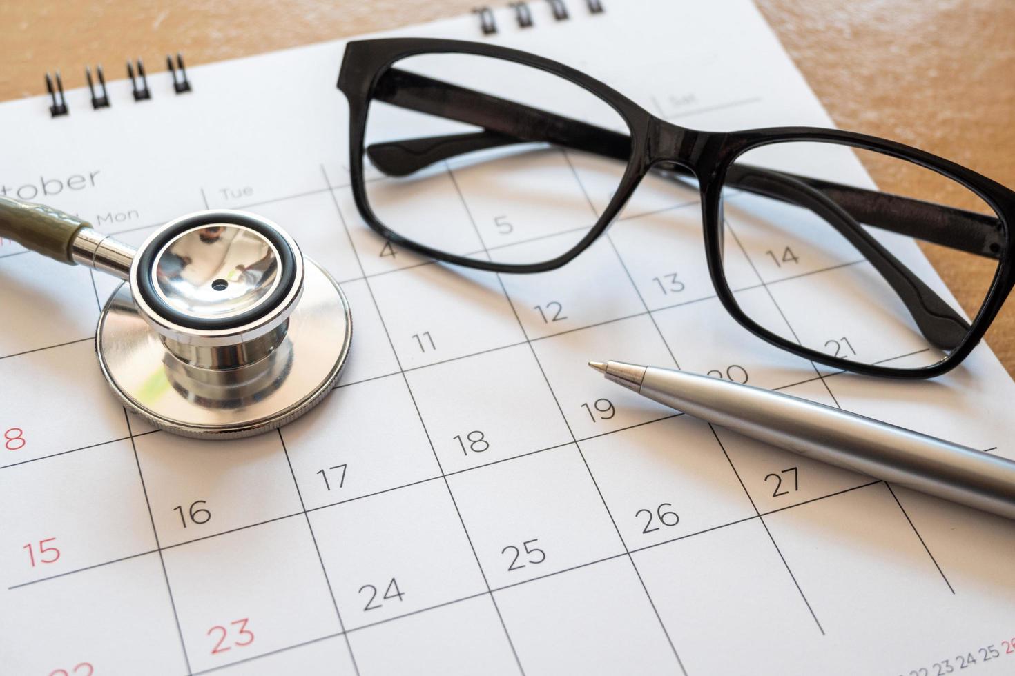 stethoscope and calendar on wooden table, schedule to check up healthy concept photo