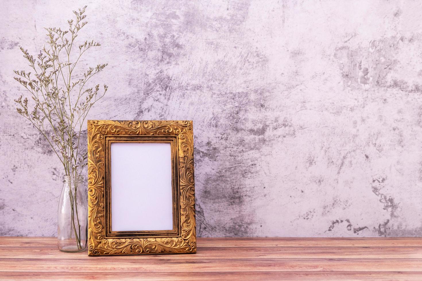 Picture frame with flowers on wall background and wooden table. Poster product design styled photo