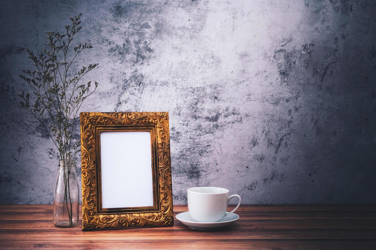 marco de fotos y flores y tazas de café en la mesa de madera. cartel de diseño de producto con estilo