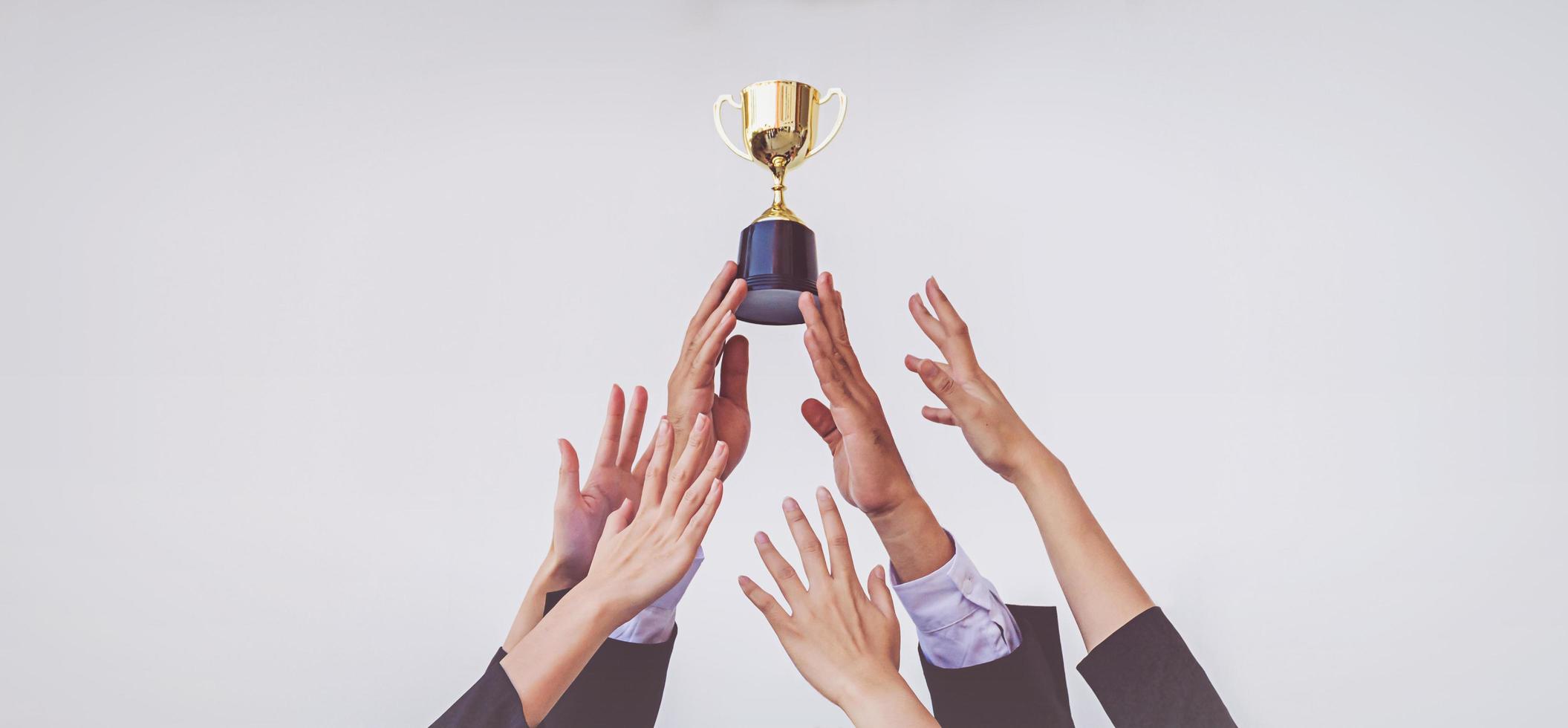 Hands scramble for the golden trophy cup, concept business photo
