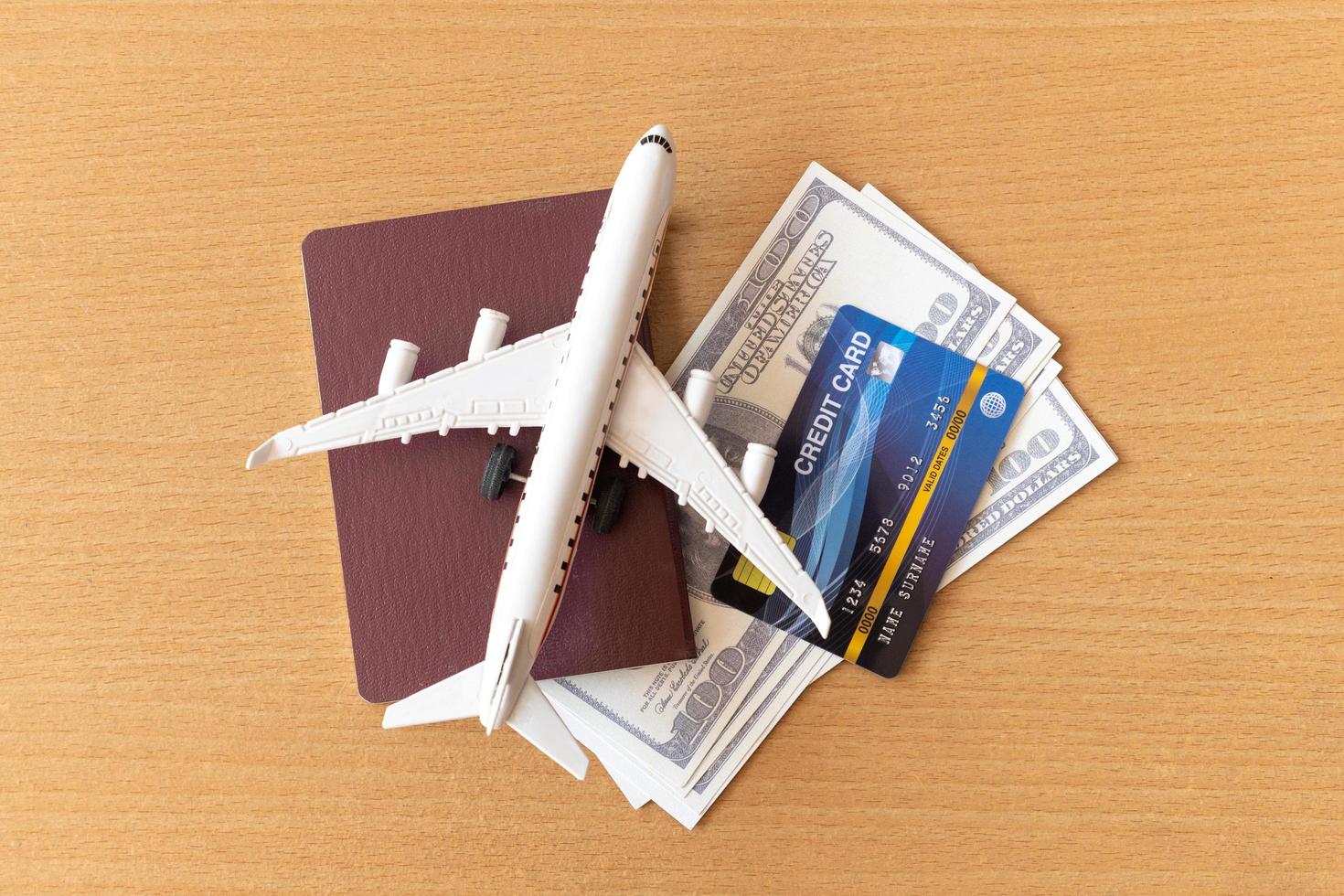Toy airplane, credit cards, dollars and passport on wooden table. Travel concept photo
