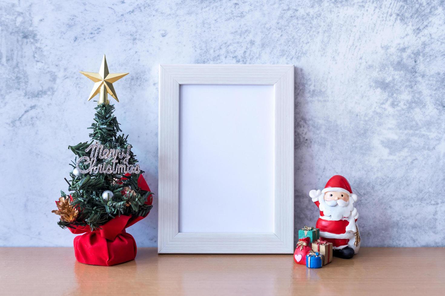 Picture frame and Christmas decoration - Santa Clause, tree and gift on wooden table. Christmas and Happy new year concept photo