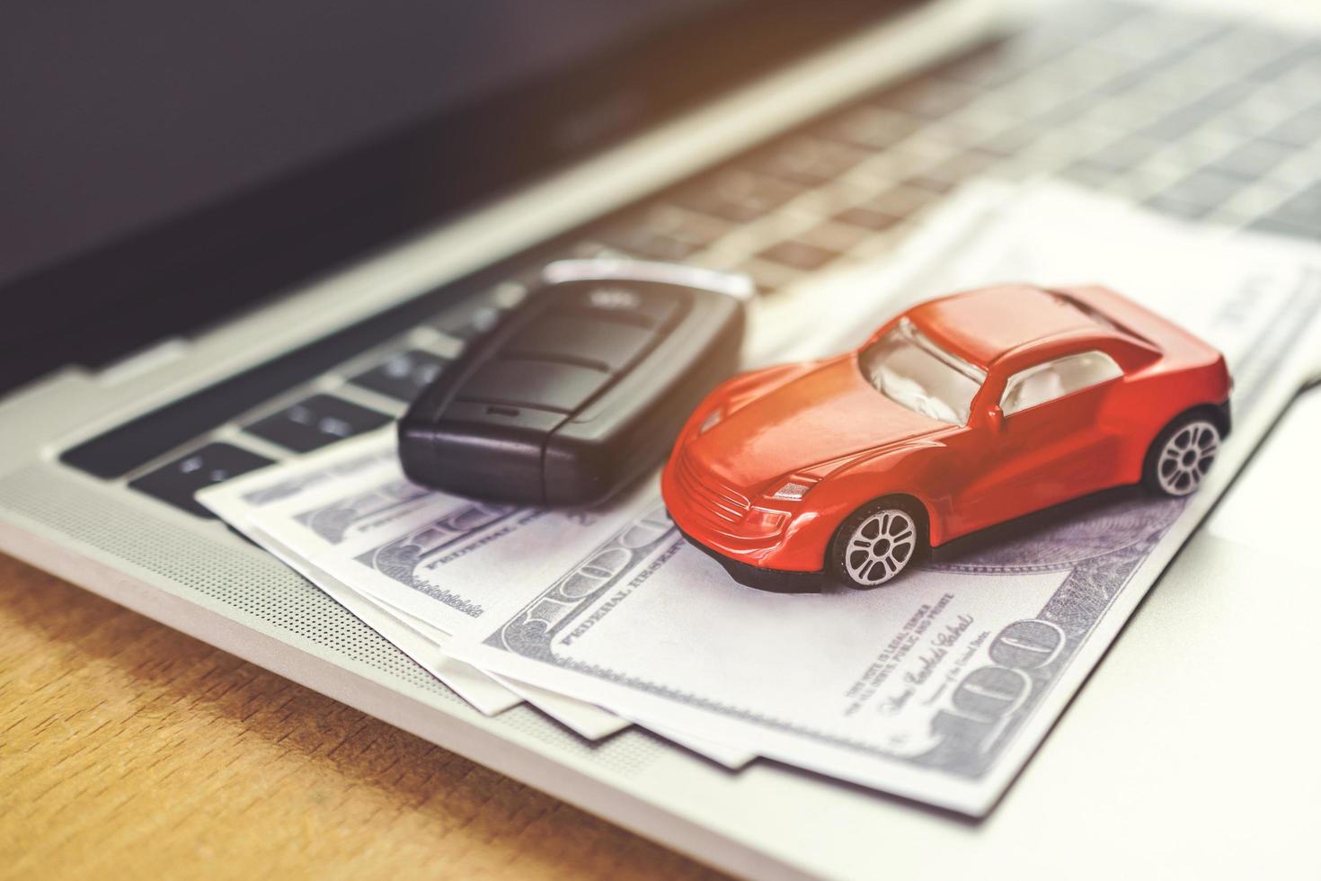 Car model, money and Notebook on wooden desk. shopping online and car payment by using laptop photo