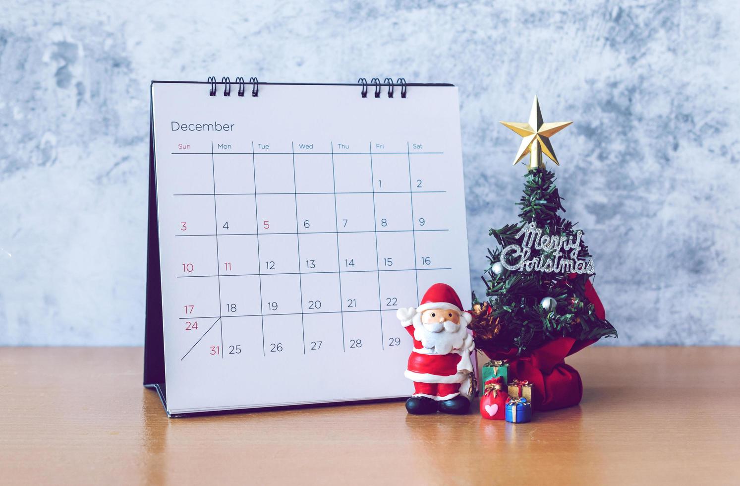 calendario de diciembre y decoración navideña - santa claus, árbol y regalo en mesa de madera. concepto de navidad y feliz año nuevo foto