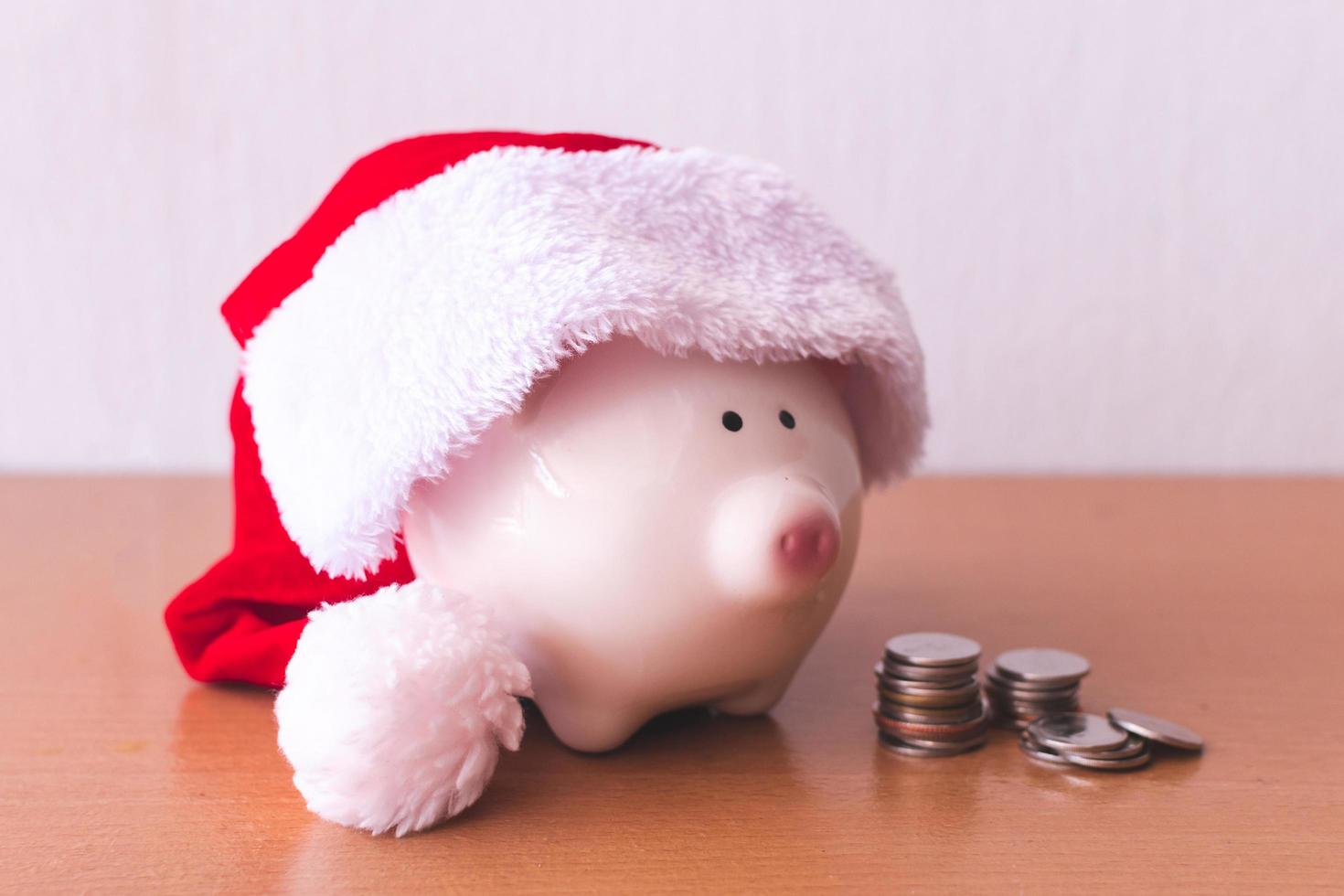 Piggy bank with Santa Claus hat and coins on Wooden table photo