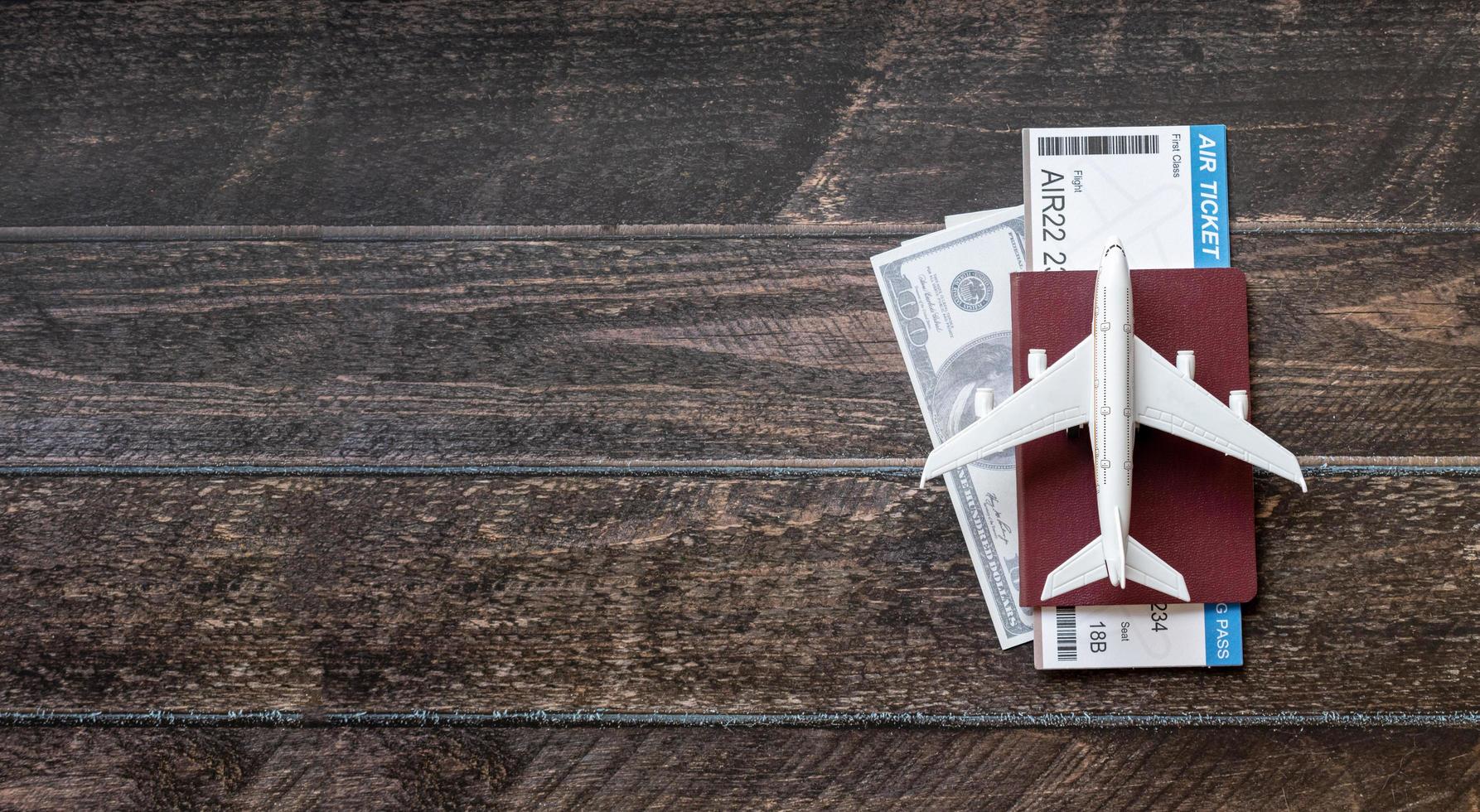 Toy airplane, Air Ticket, credit cards, dollars and passport on wooden table. Travel concept photo