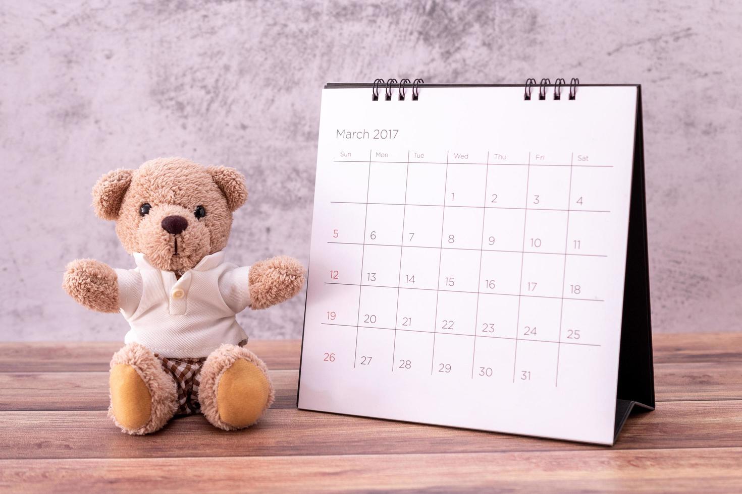 oso de peluche con calendario en mesa de madera. celebración del día de san valentín foto