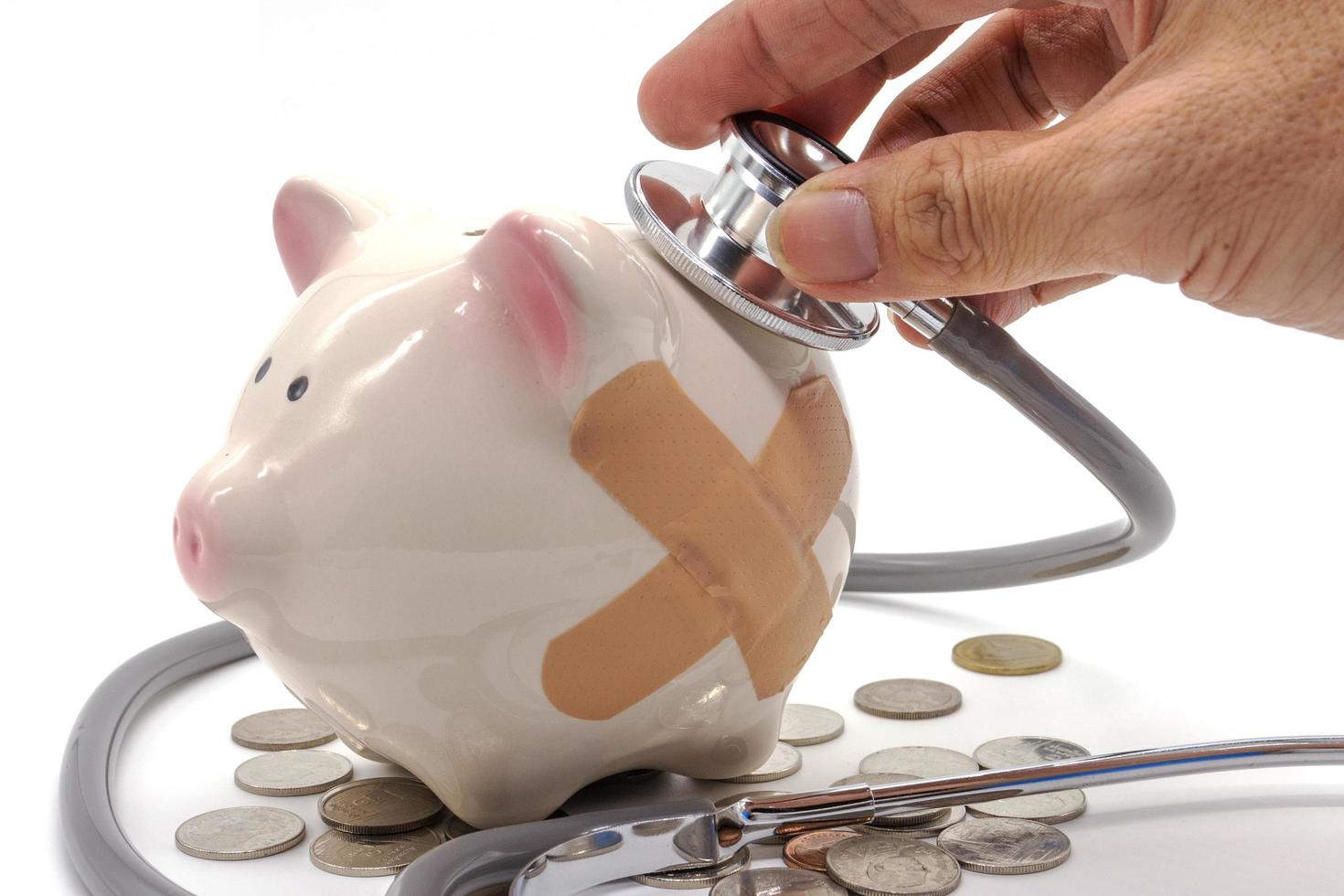 Doctor Holding Stethoscope to Piggy Bank photo