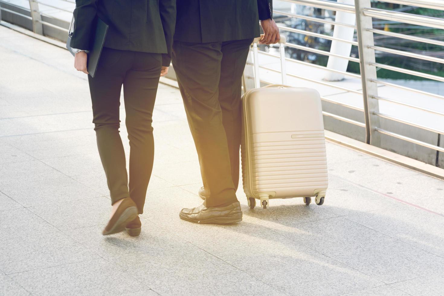 Businessman and Businesswoman pulling a suitcase in a big city. photo