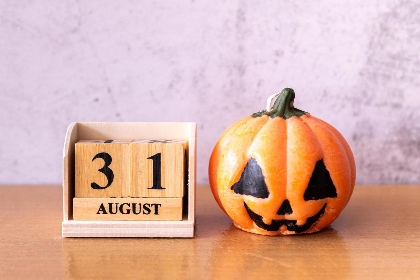 Wooden calendar block disrupted show date 31 october halloween day and toy pumpkin on wooden background. Halloween concept photo