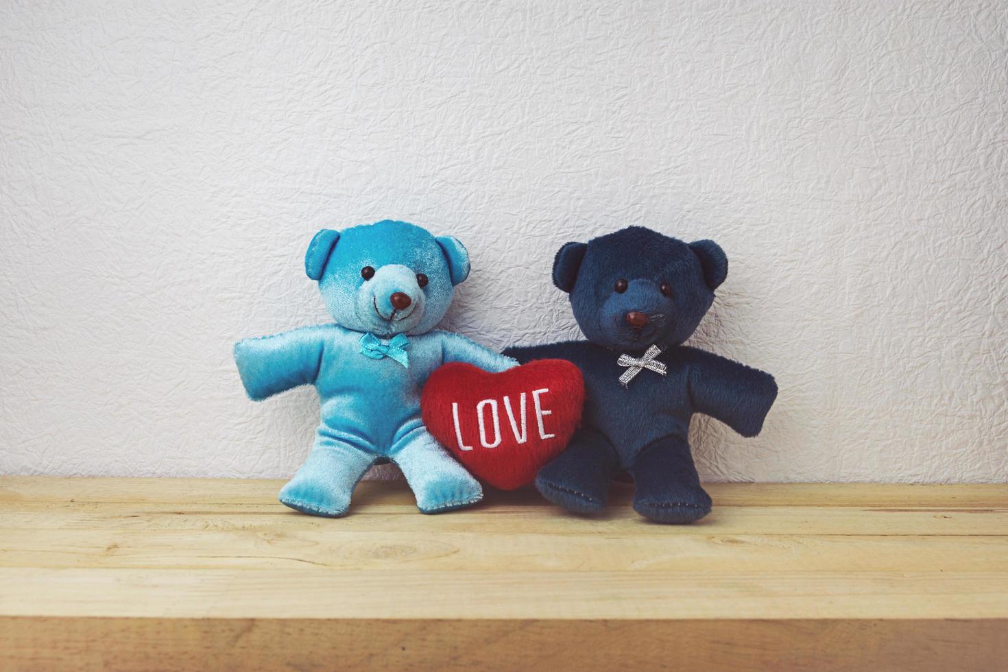 encantador oso de peluche y forma de corazón rojo sentado en la mesa de madera foto