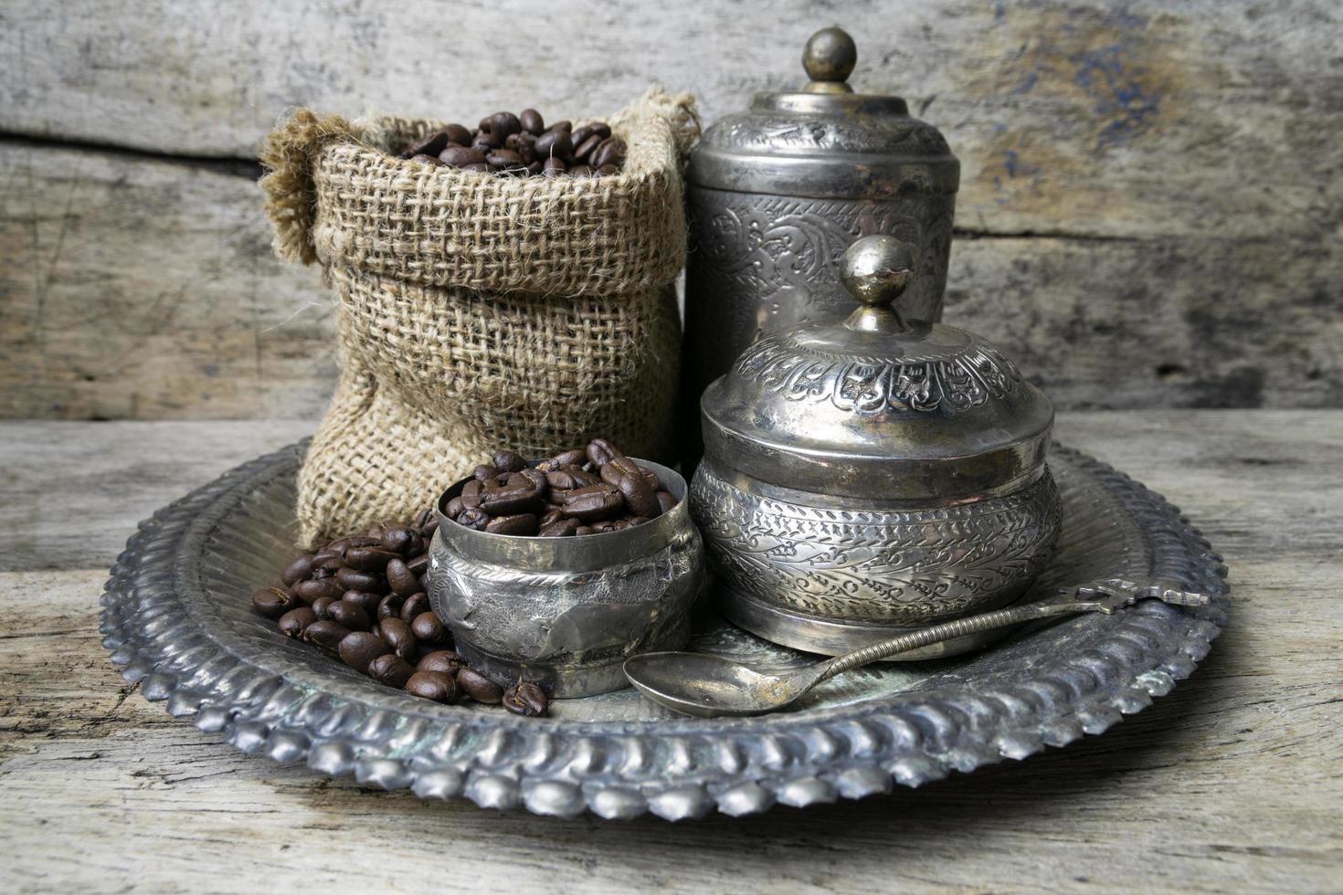 Silver cup and Coffee beans in sackcloth bag on wooden background photo