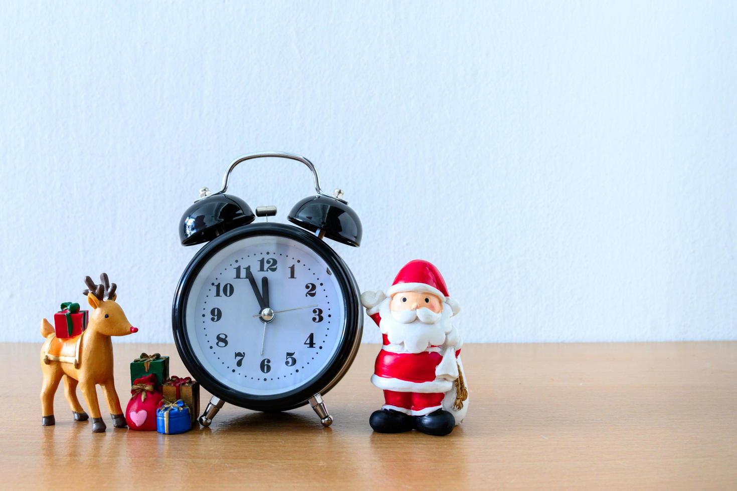 Santa Claus and clock, deer and gift on table. Happy New Year and Xmas Concept photo