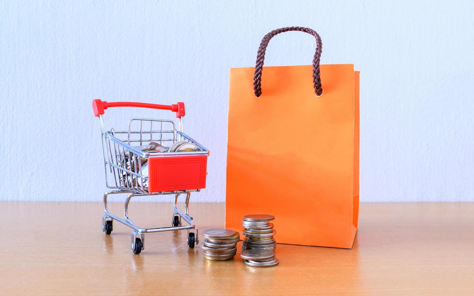 Cart supermarket and orange paper bag on wood table. shopping concept photo