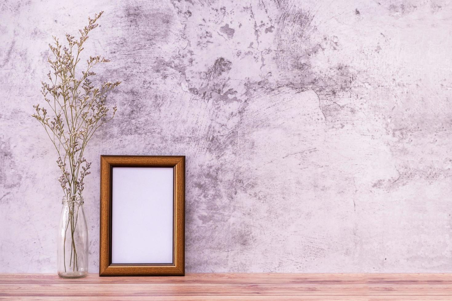 marco de fotos con flores sobre fondo de pared y mesa de madera. cartel de diseño de producto con estilo