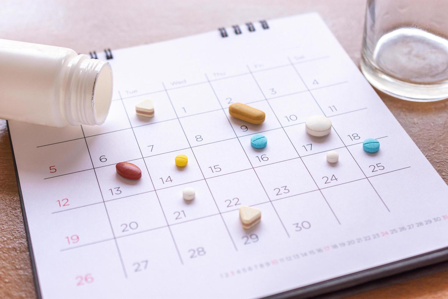 un montón de pastillas diferentes en un fondo de calendario. concepto de salud foto