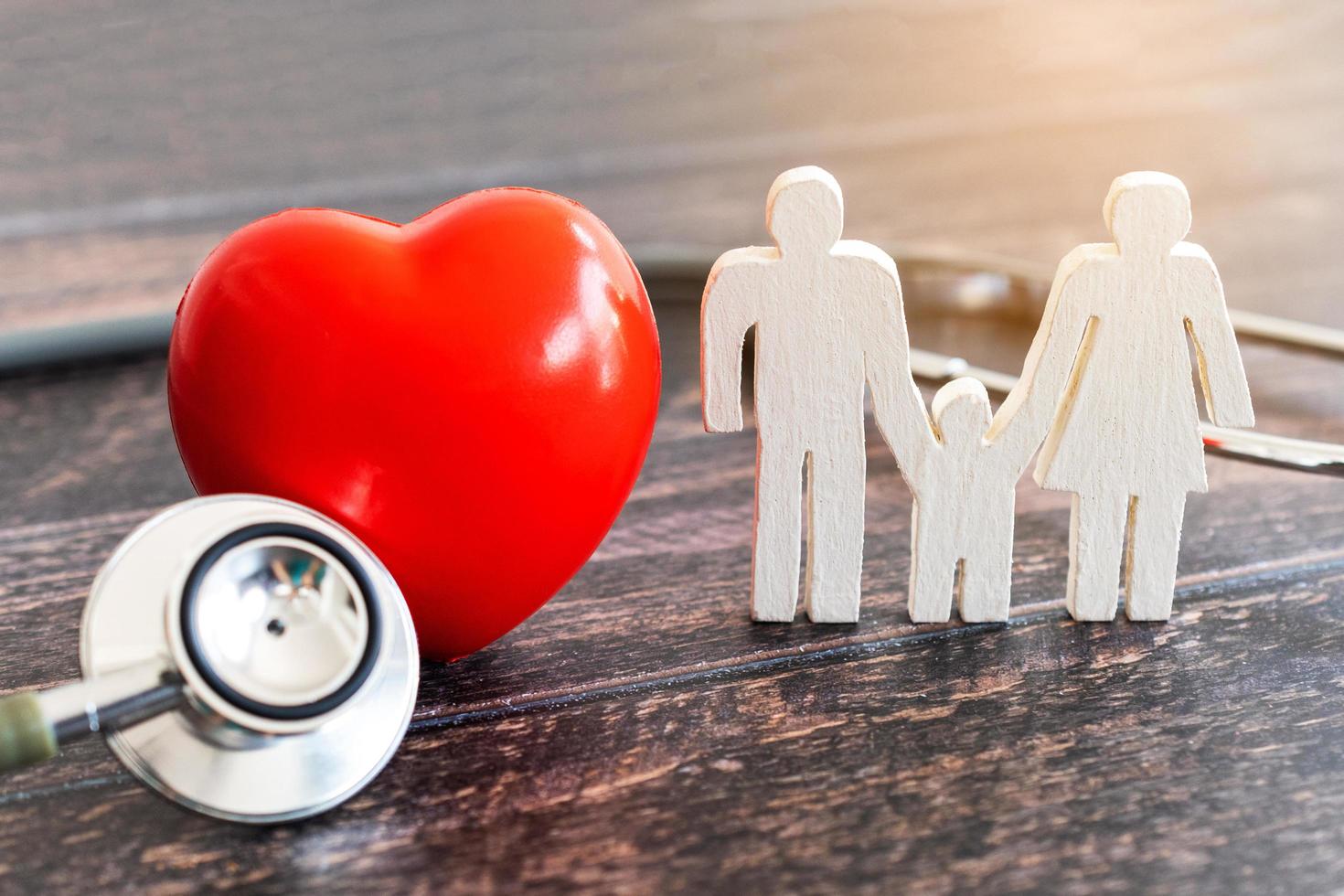 familia roja del corazón, del estetoscopio y del icono en el escritorio de madera. concepto de seguro médico foto