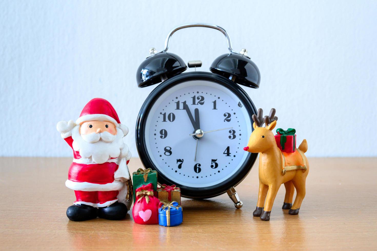 santa claus y reloj, ciervo y regalo en la mesa. feliz año nuevo y concepto de navidad foto