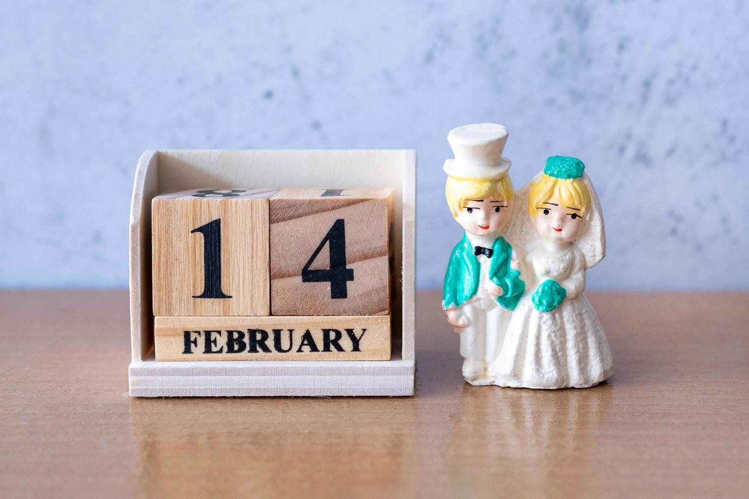 pareja de bodas en miniatura con calendario de madera 14 de febrero. día de San Valentín foto