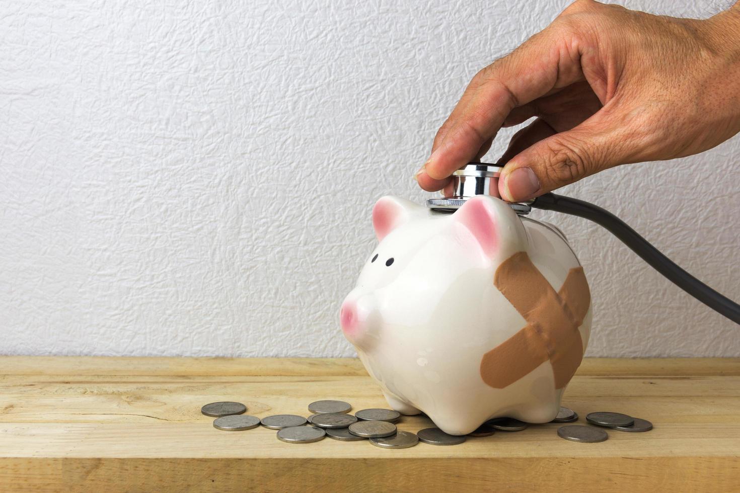 Doctor Holding Stethoscope to Piggy Bank photo