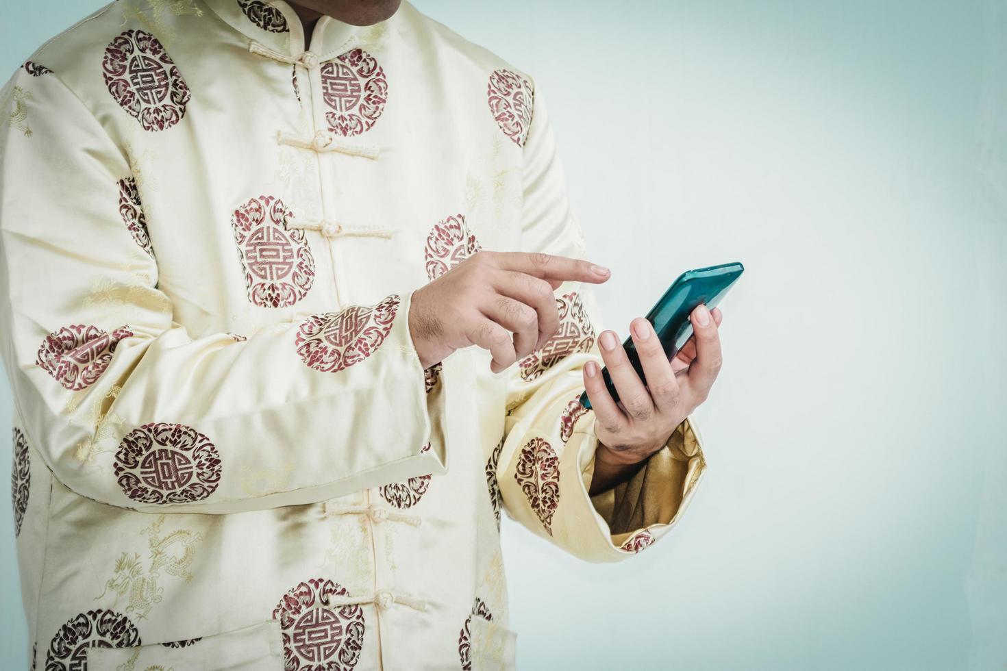 hombre asiático con cheongsam con teléfono inteligente. foto