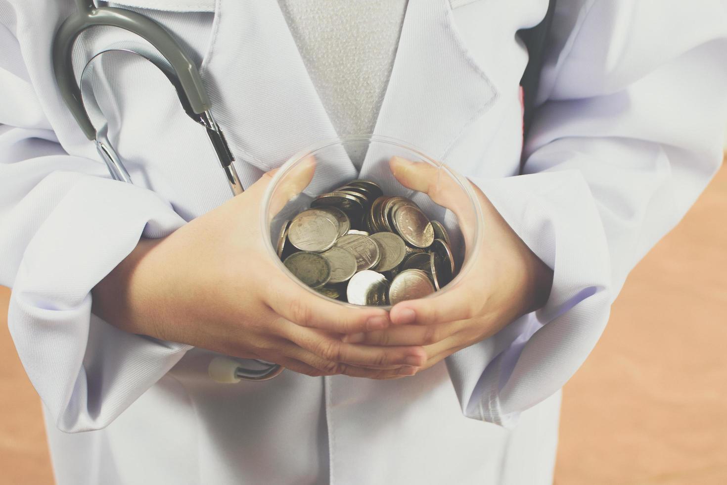Asian girl playing as a doctor care money in cup photo