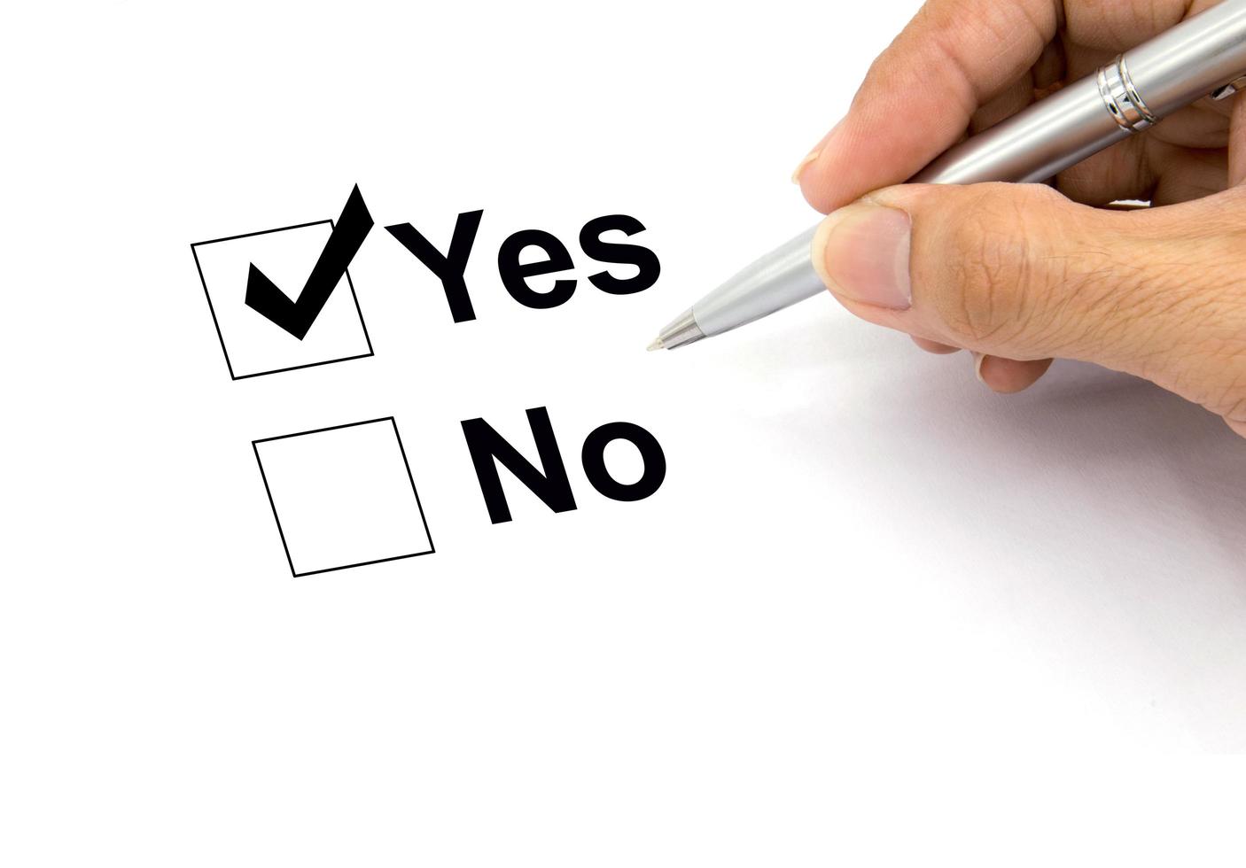 Man hand with pen over document, select Yes. photo