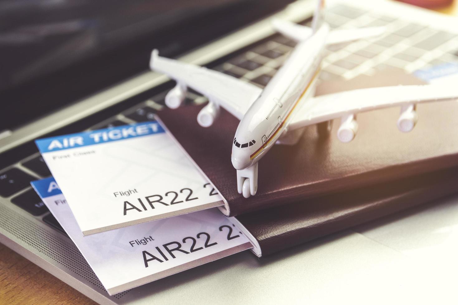 Air tickets and passports near laptop computer and airplane on table. Online ticket booking concept photo