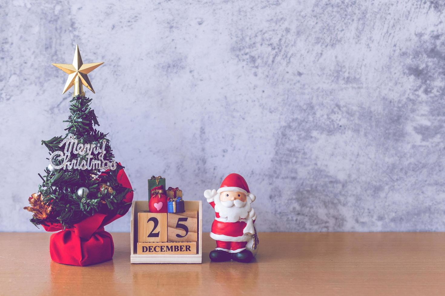 fecha del calendario del bloque 25 de diciembre calendario y decoración navideña - santa claus, árbol y regalo en la mesa de madera. concepto de navidad y feliz año nuevo foto