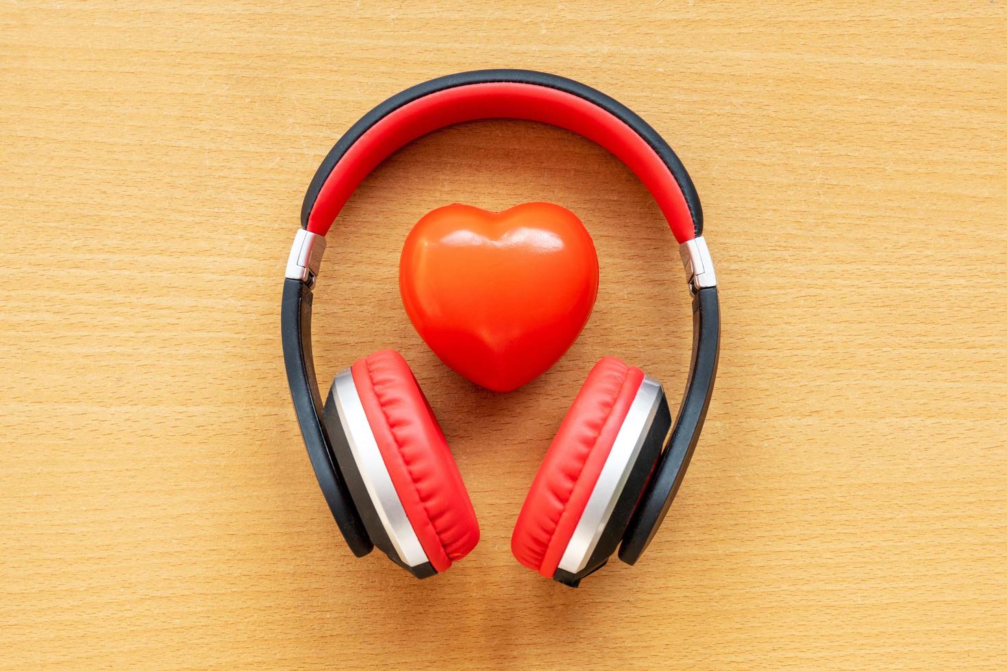 auriculares y corazón rojo en el escritorio de madera. concepto musical foto