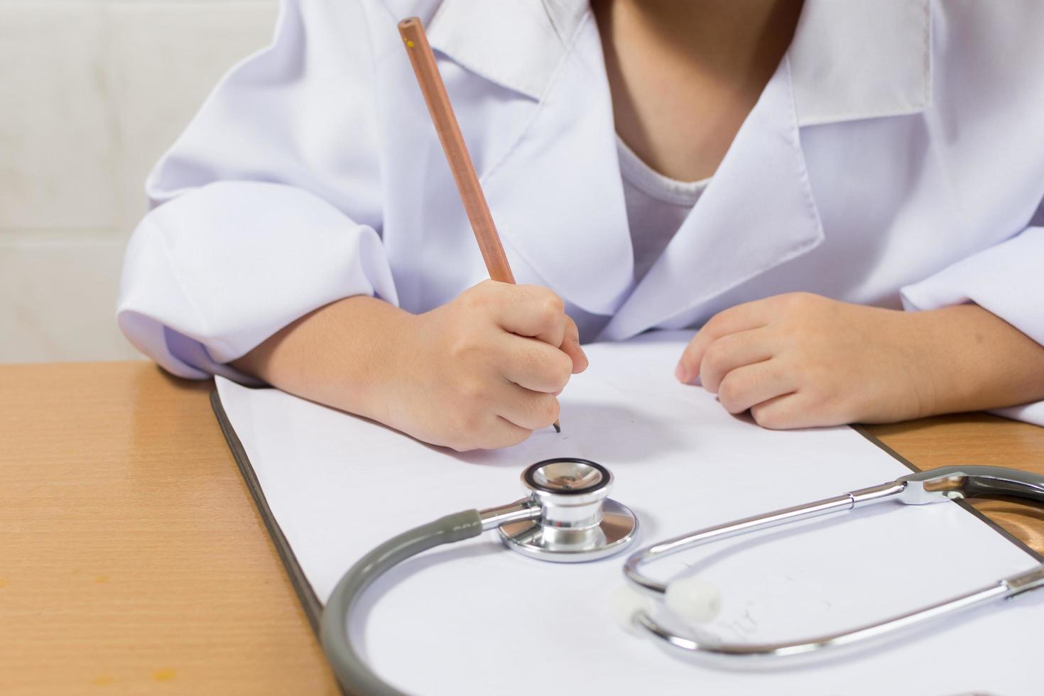 Asian girl wearing as a doctor writing prescription and preparing patients report photo