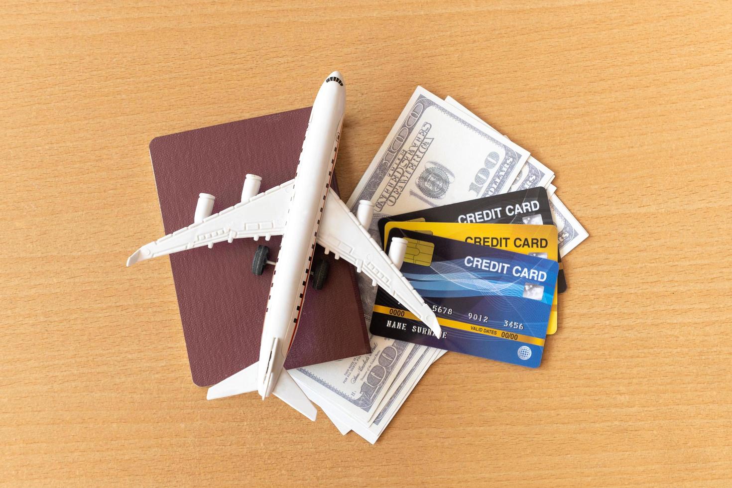 Toy airplane, credit cards, dollars and passport on wooden table. Travel concept photo