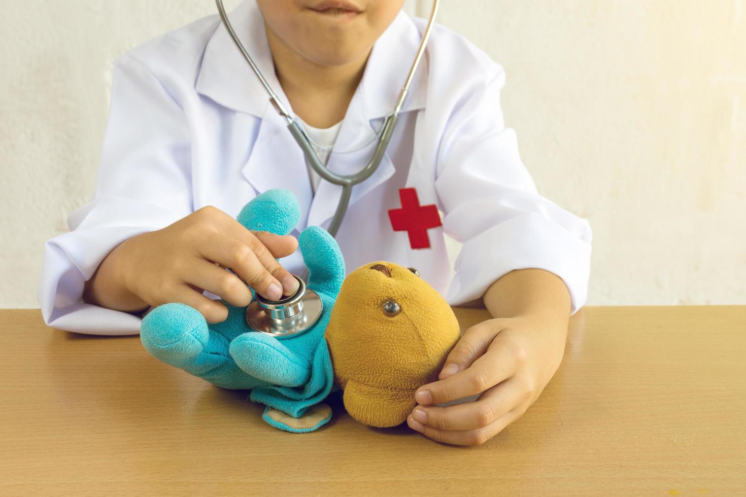 niño asiático jugando como una muñeca de oso de atención médica foto