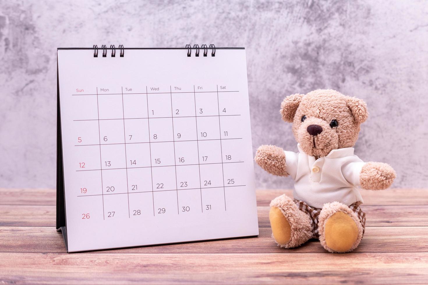 oso de peluche con calendario en mesa de madera. celebración del día de san valentín foto