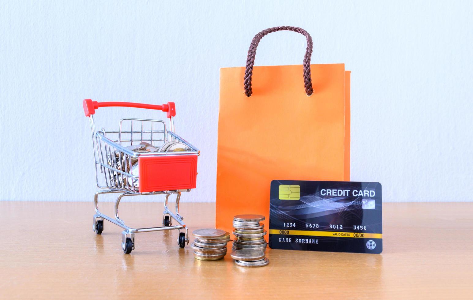 Cart supermarket and orange paper bag on wood table. shopping concept photo