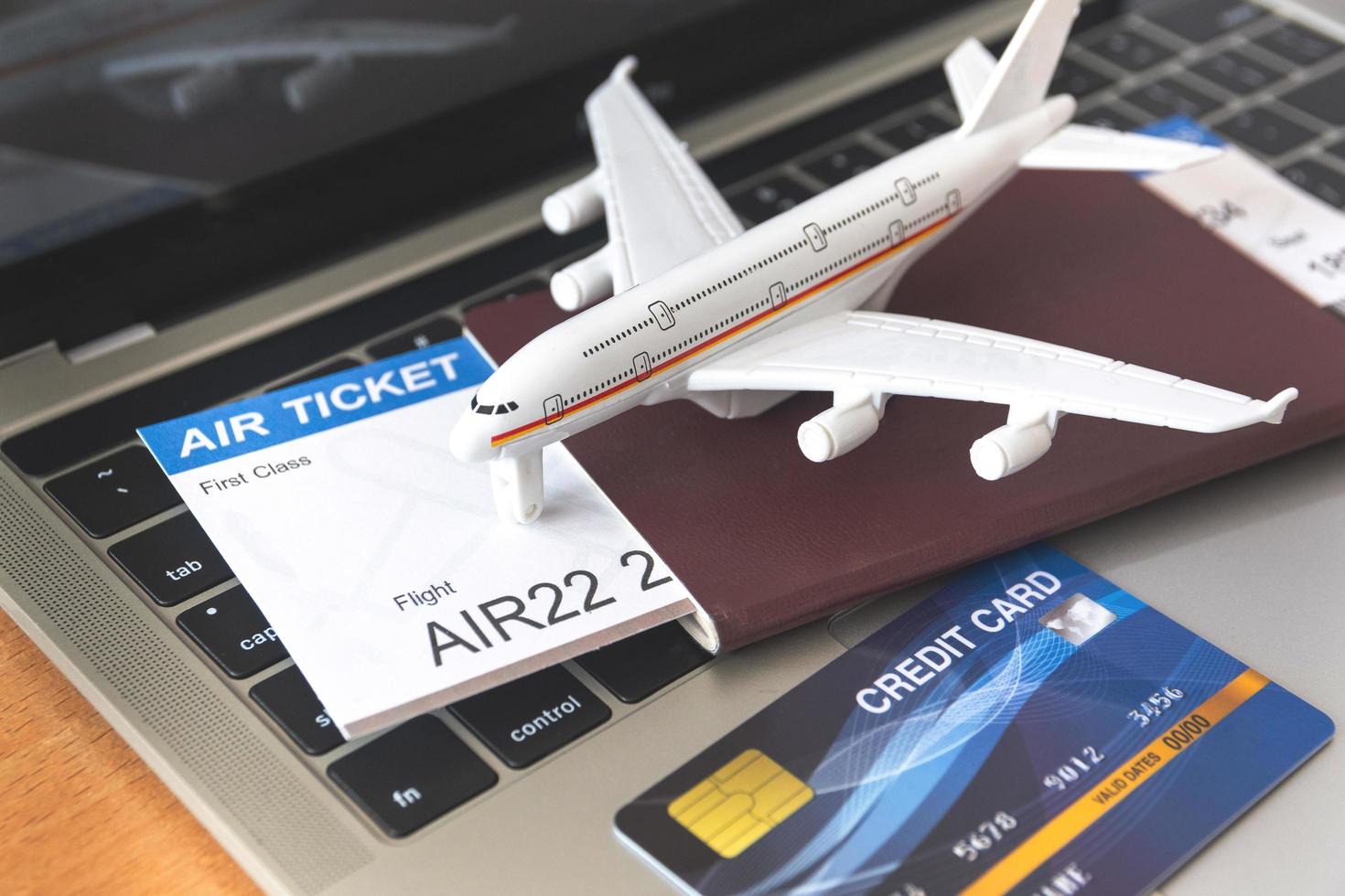 Air tickets and passports near laptop computer and airplane on table. Online ticket booking concept photo