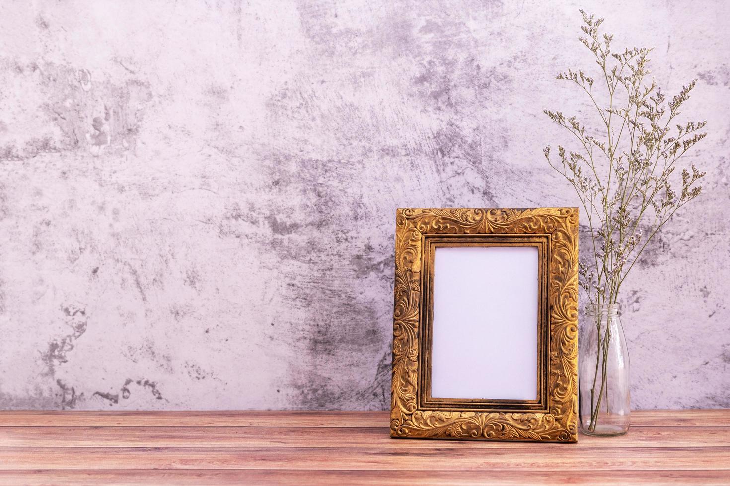 Picture frame with flowers on wall background and wooden table. Poster product design styled photo