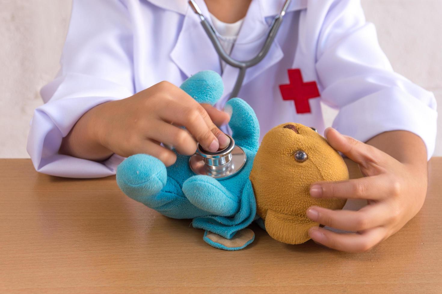 niño asiático jugando como una muñeca de oso de atención médica foto