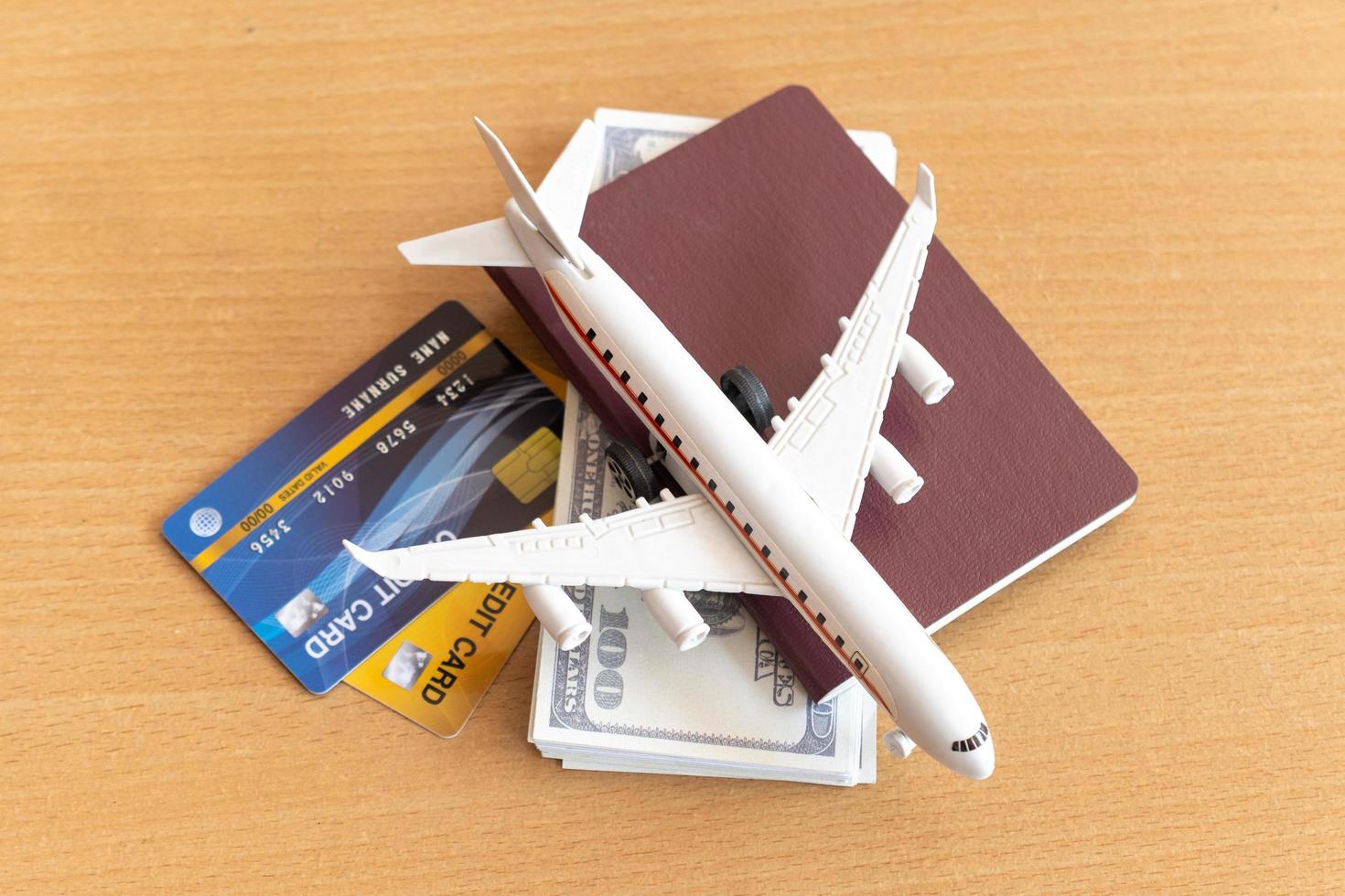 Toy airplane, credit cards, dollars and passport on wooden table. Travel concept photo