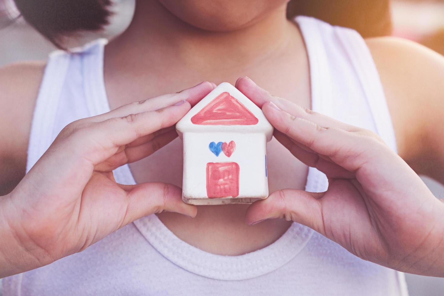 Small kid hands holding house photo