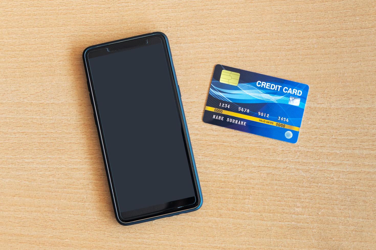tarjeta de crédito y teléfono inteligente en la mesa. compras en línea en internet usando un teléfono inteligente foto