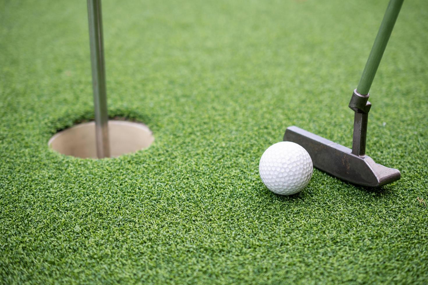 Golf ball and golf club on artificial grass. photo