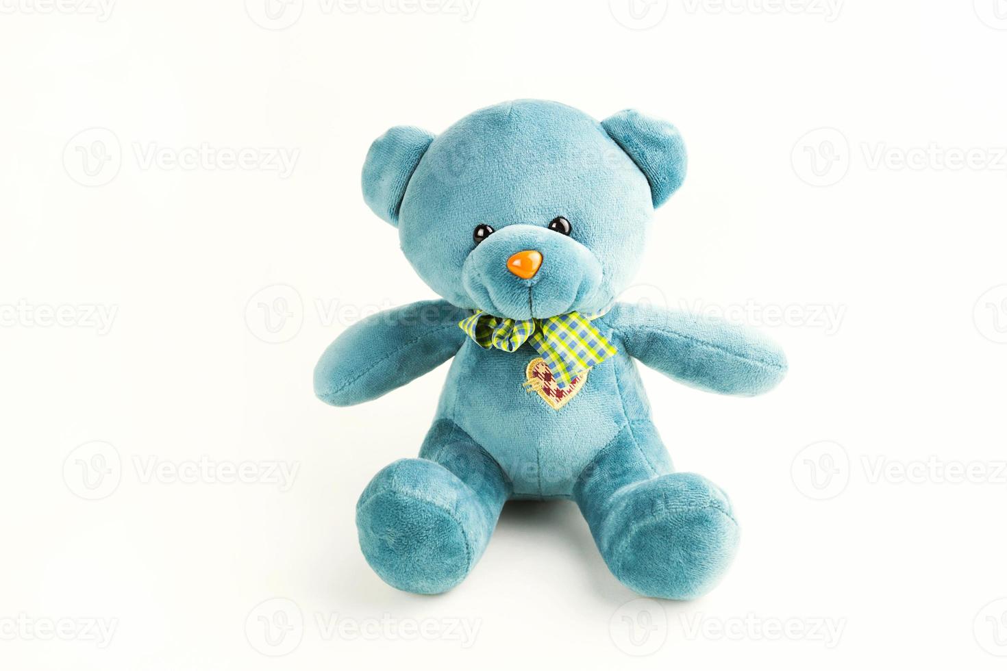 Turquoise soft teddy bear with checkered scarf and embroidered heart on the chest on a white background. Children's toy. Love, a gift to a girl, a declaration of love, Valentine's day. Copy space photo