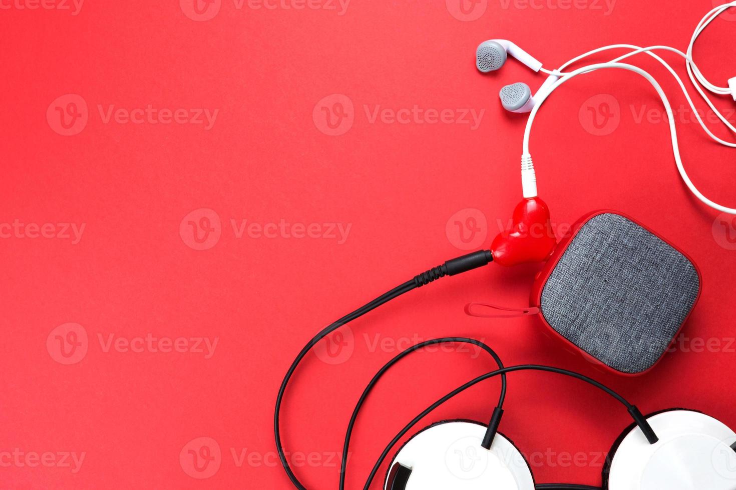 un divisor de auriculares en forma de corazón para una pareja enamorada. conectado a un altavoz portátil rojo y dos pares de auriculares: plano. día de san valentín, amor, tecnología moderna, espacio de copia foto