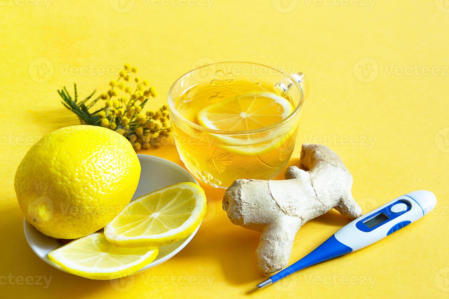 té medicinal en una taza, jengibre, limón, acacia-fortalece el sistema inmunológico en la estación fría, termómetro - plano. bebida vitamínica para la salud e ingredientes sobre fondo amarillo. foto