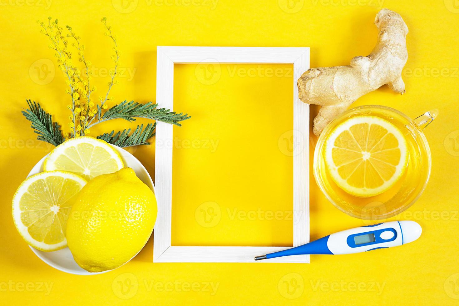 Medicinal tea in a cup, ginger, lemon, acacia-strengthen the immune system in cold season, thermometer and copy space, sheet for notes. Vitamin drink for health and ingredients on yellow background. photo