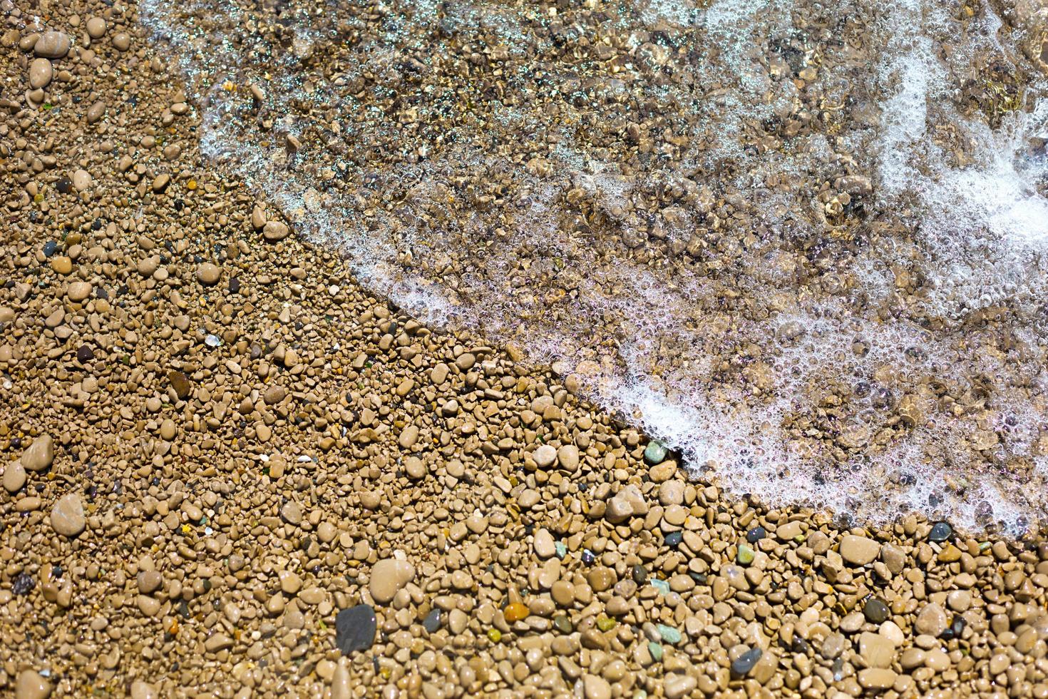 Sea wave on a pebble beach made of small stones. Sea holidays, travel background photo