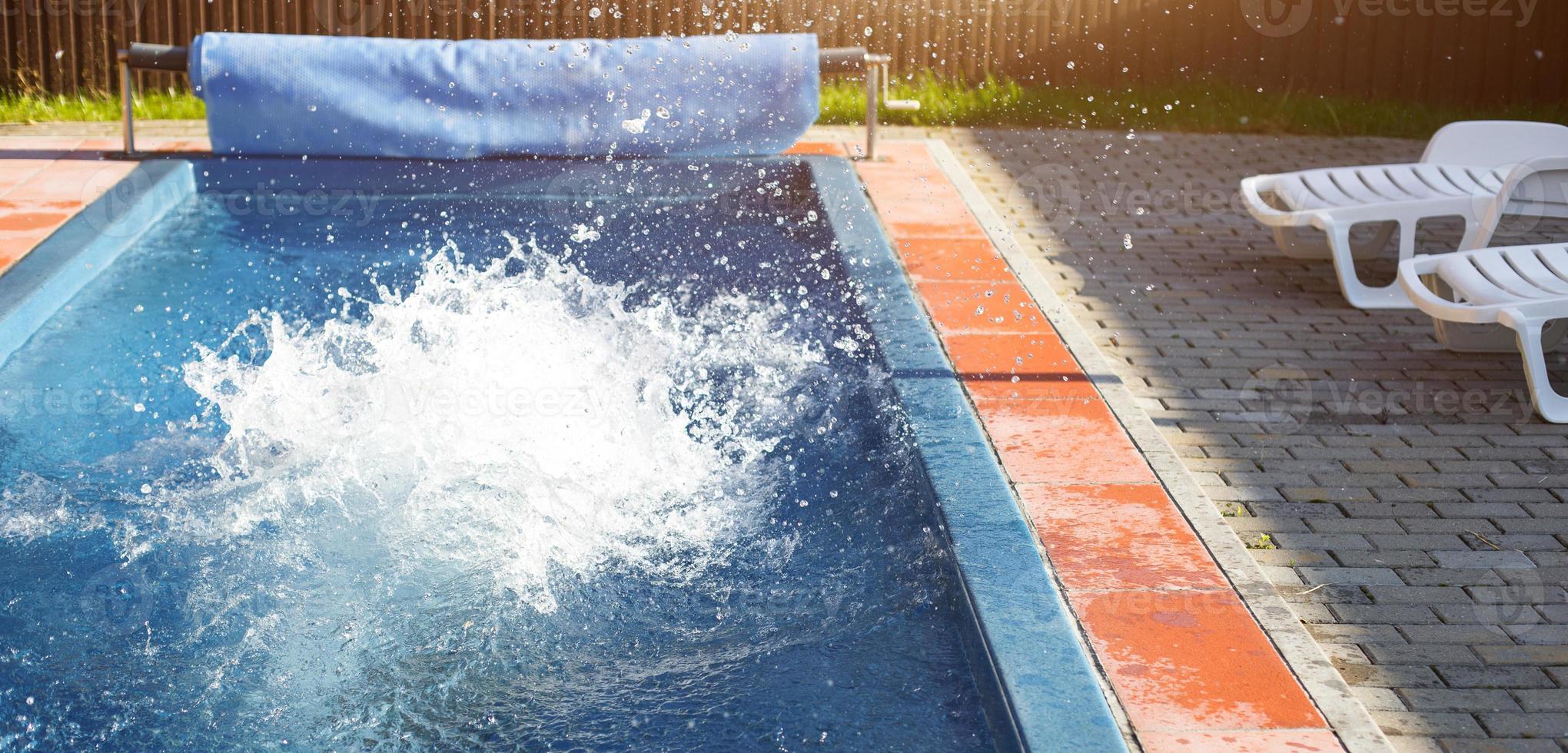 Splashes in the outdoor swimming pool near the white deck chairs. Recreation area at the resort, ticket to the hotel, sauna and spa, sports and swimming. Copy space photo